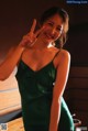 A woman in a green dress making a peace sign.