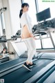 A woman is standing on a treadmill in a gym.