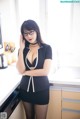 A woman in a black and white dress standing in a kitchen.