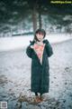 A woman standing in the snow wearing a black coat.