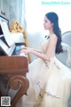 A woman in a white dress sitting at a piano.