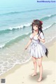 A girl in a white dress standing on a beach.