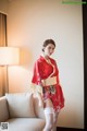 A woman in a red kimono standing next to a white couch.