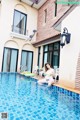 A woman sitting on the edge of a swimming pool.