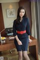 A woman in a blue dress sitting at a desk.