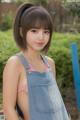 A young woman in a denim dress posing for a picture.