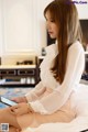 A woman sitting on a bed looking at her phone.