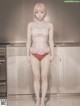 A woman in a pink lingerie standing in a kitchen.