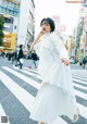 A woman in a white dress is crossing the street.