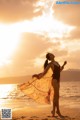 A woman standing on a beach with her arms outstretched.