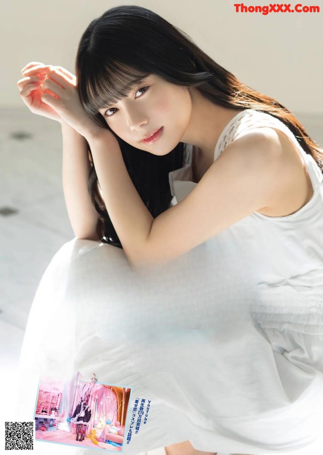 A woman in a white dress sitting on the floor.