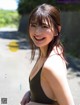 A woman in a black bathing suit smiles at the camera.