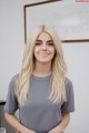 A woman with long blonde hair standing in front of a whiteboard.